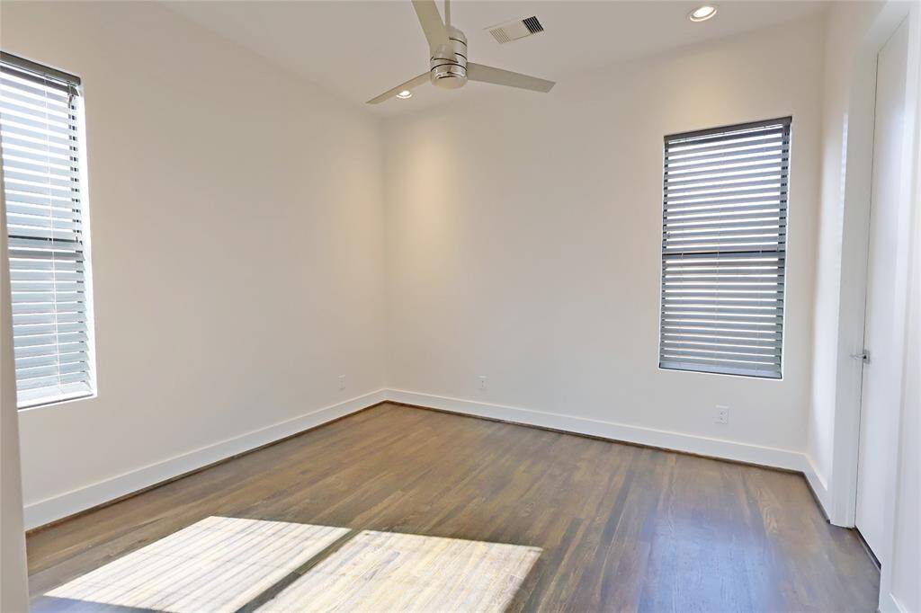 The third bedroom boasts high ceilings, recessed lighting, and a sleek modern ceiling fan.