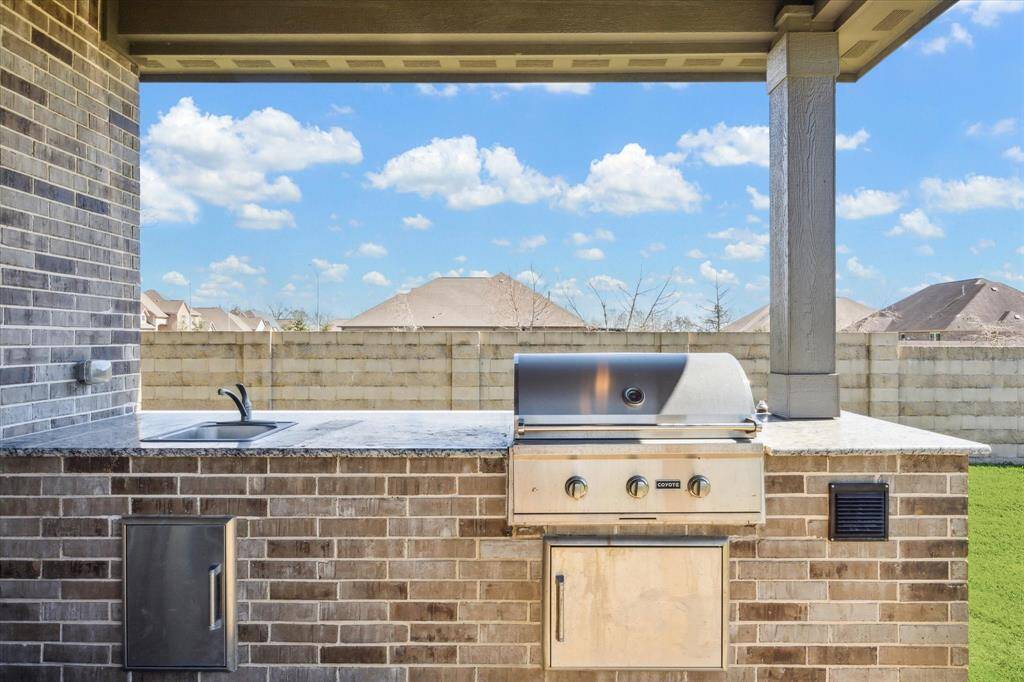 Covered patio with outdoor kitchen featuring sink and gas grill.  Perfect for entertaining!