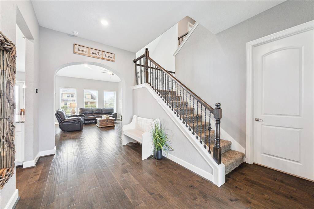 The grand entry features elegant arches, abundant natural light, and showcases the stunning wood floors found throughout the first floor common areas.