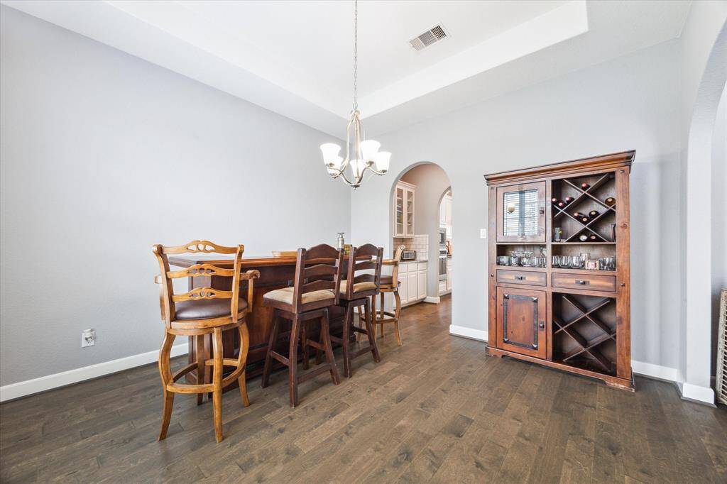 On the other side of the Butler's Pantry, you'll find an elegant dining room with a tray ceiling, chic chandelier, and neutral tones, perfect for hosting all your guests.