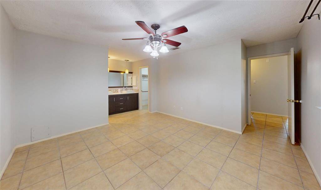 Stepping down the hall into the primary bedroom, it's also fully-tiled with a lighted ceiling fan.
