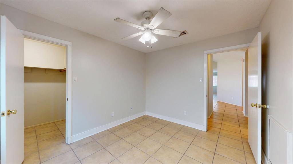 One of the secondary bedrooms, showing the tile floor and lighted ceiling fan.