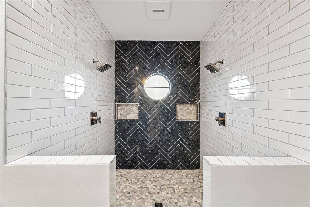 Experience spa-like luxury with this spacious, dual-head shower, featuring sleek, modern tiling.
