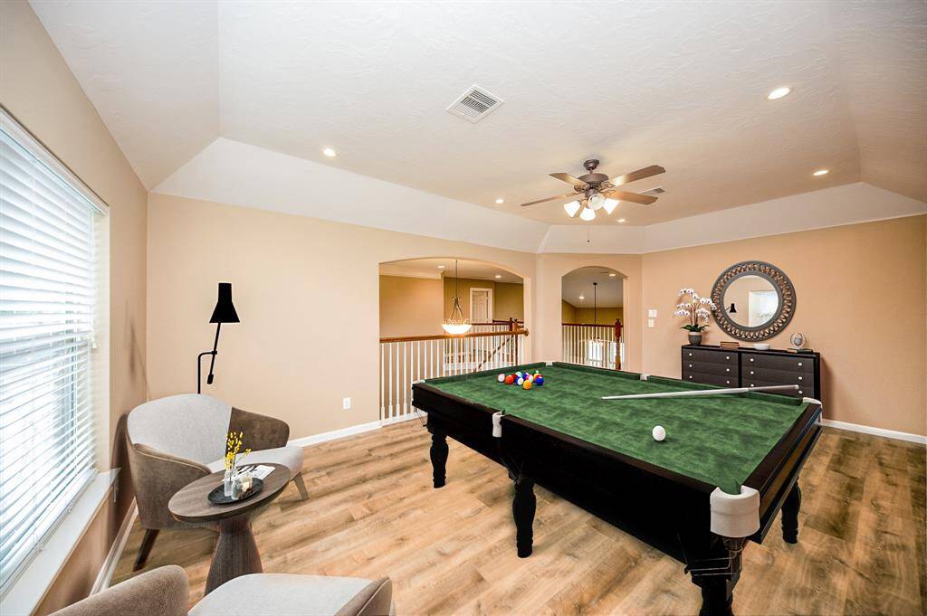 This spacious game room features modern flooring, and ample natural light. The room includes a ceiling fan and recessed lighting making it ideal for entertainment and relaxation.  Image is Virtually Staged.