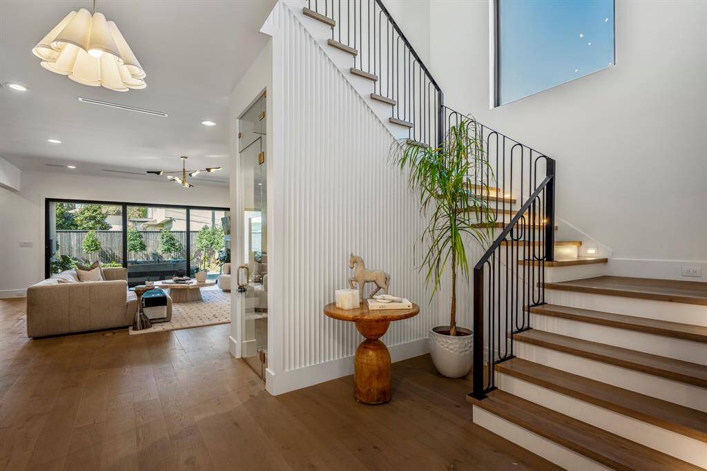 This grand foyer is adorned with a stately fluted wood wall for elevated elegance. Illuminated risers on the stairs.