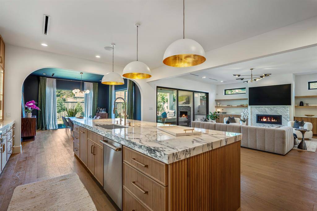 Marble island features a pull-out trash drawer, storage drawers on each end of the island, and a Monogram 24" Fully Integrated Dishwasher.
