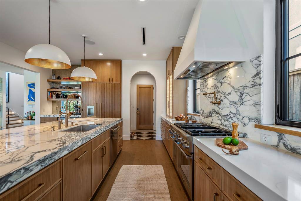 Thermador 48-inch Gas Range with a griddle and a Zephyr custom vent hood adorned by Italian backsplash. Counters on the right are Michelangelo quartz.