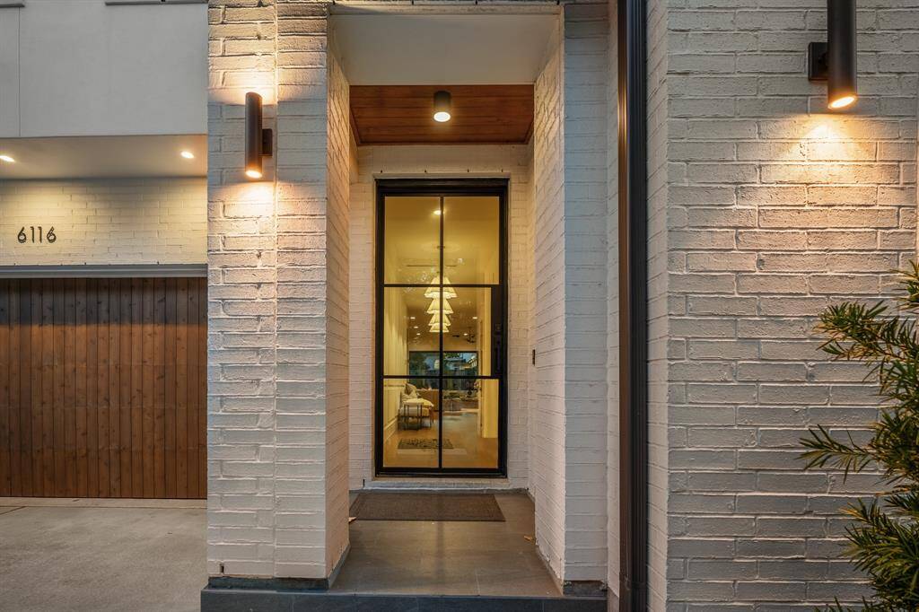 The front entry at twilight. A covered brick entry with sconce lighting welcomes your friends and family. Architect: Two Sketch. Designer: The homeowners.