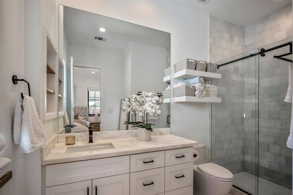 Welcome inside this beautiful en-suite bathroom with a walk-in shower, marble counters, Toto toilet, and recessed shelves for storage.