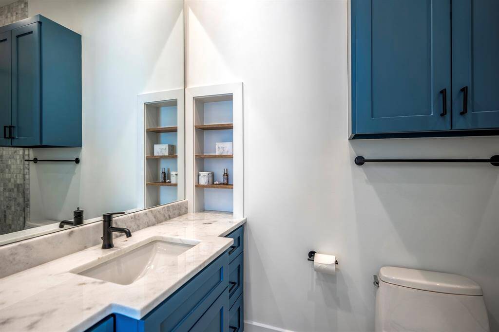 This en-suite bathroom includes a Kohler toilet, marble counters, and a bathtub.