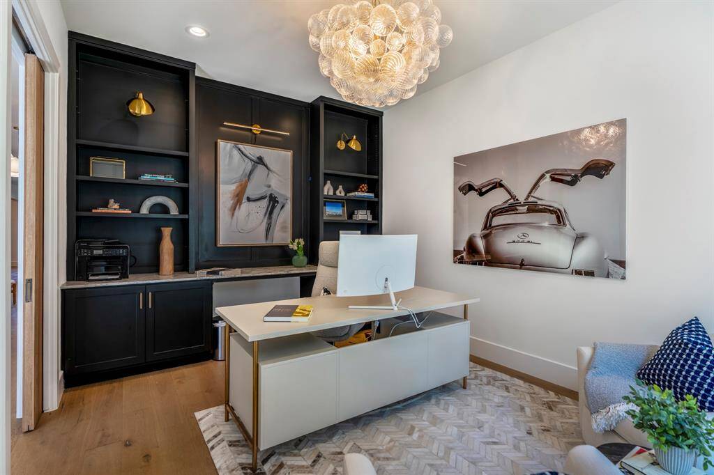 Built-in shelves and cabinets provide plenty of storage in this study/home office. Designer lighting fixture is the Visual Comfort Signature Collection Talia Large Chandelier.