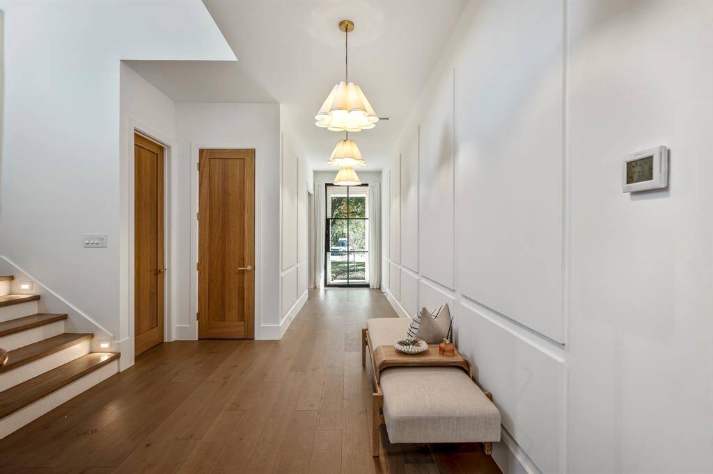 A grand promenade of elegance, where designer pendant lights create an inviting space to welcome your friends and family. The closed door facing us is the coat closet. The closed door to the left leads to a full first floor bathroom.
