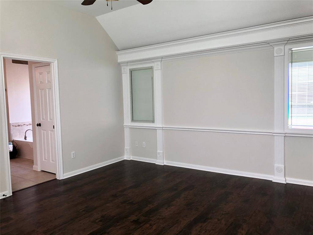 Elegant master bedroom with wood looking floors and vaulted ceilings with fan.
