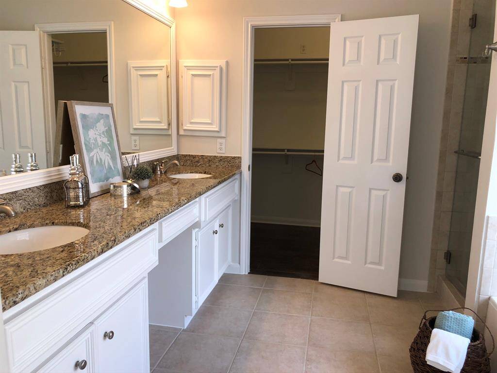 Master bathroom with double sinks, granite countertops and vanity seating area.