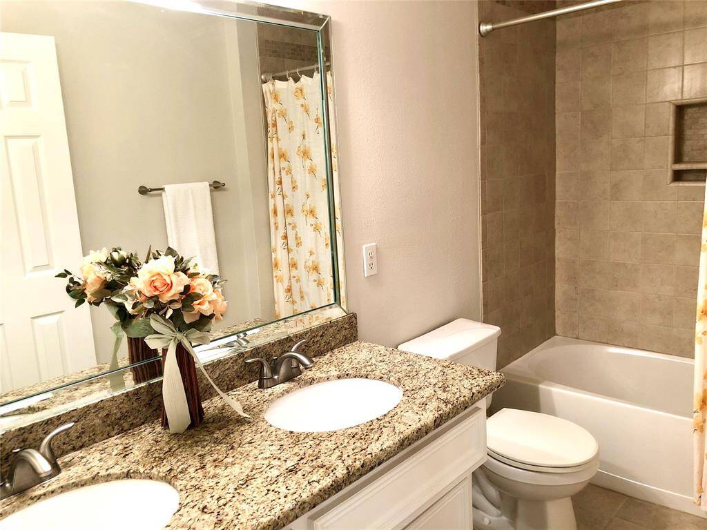 Secondary bathroom with double sinks, granite countertops  and shower with tub.