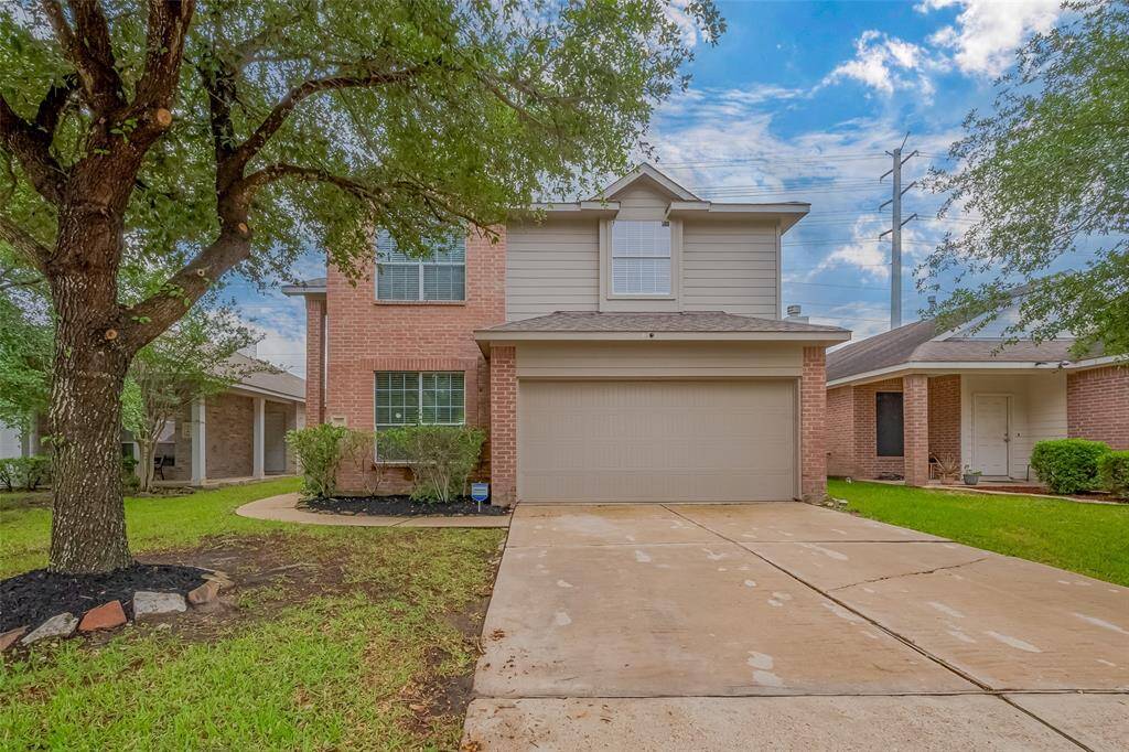 This is a two-story brick home with a two-car garage. The property has a well-maintained front yard with a large tree and a spacious driveway. The exterior is a mix of brick and siding, offering a classic and inviting appearance.