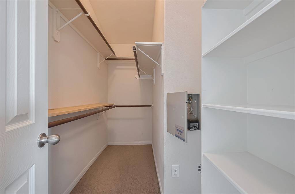 Walk-in closet with built-in shelves and hanging rods, offering ample storage and organization for clothing and accessories in primary suite.