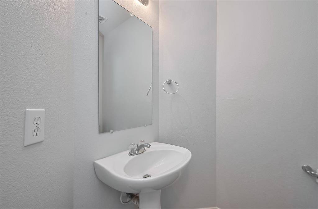Downstairs powder bath with pedestal sink and wall-mounted mirror.