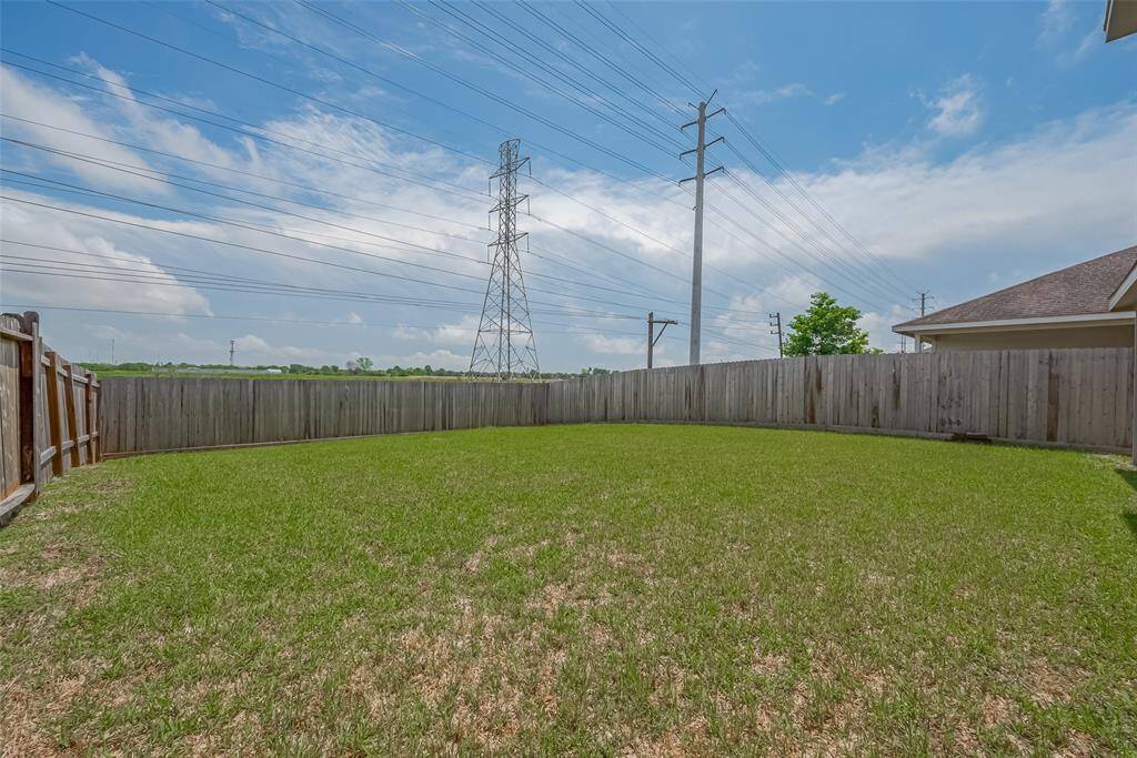 Spacious, fenced backyard with a well-maintained lawn and clear sky views. Ideal for outdoor activities or gardening.