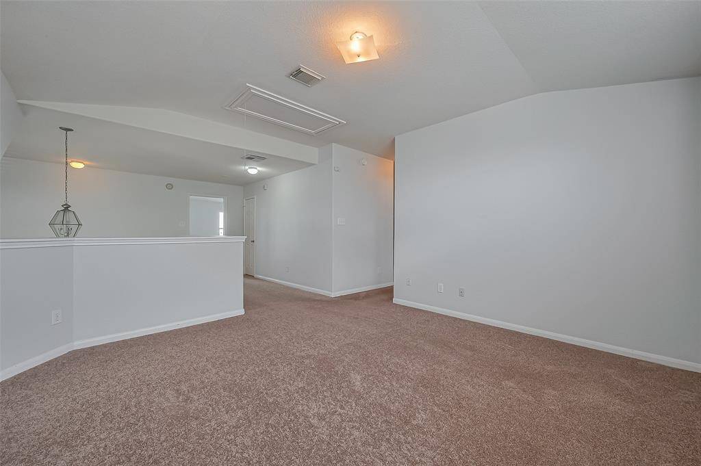 Spacious, upstairs living area with soft lighting. The walls are painted in a light, neutral color, enhancing the open feel offering potential for versatile use.