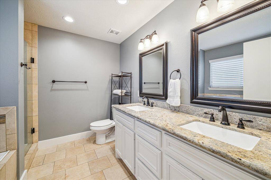 This modern primary bathroom features dual vanities, offering both style and practicality. The spacious layout ensures plenty of room for personal space while enhancing the room’s overall luxury.