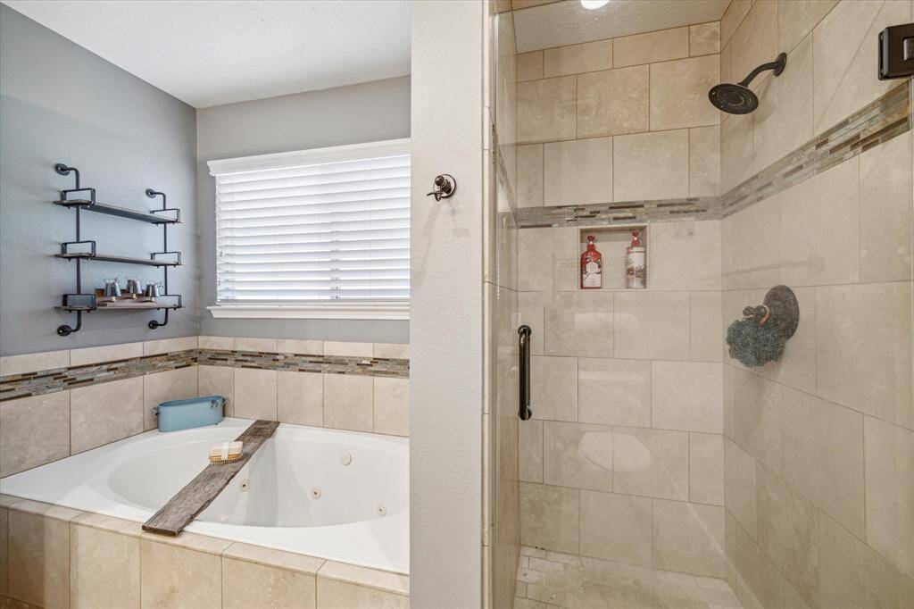 Designed for ultimate relaxation, this primary bathroom features a spacious walk-in shower and a jetted tub. Enjoy a spa-like experience right at home with these luxurious amenities, perfect for unwinding after a long day.