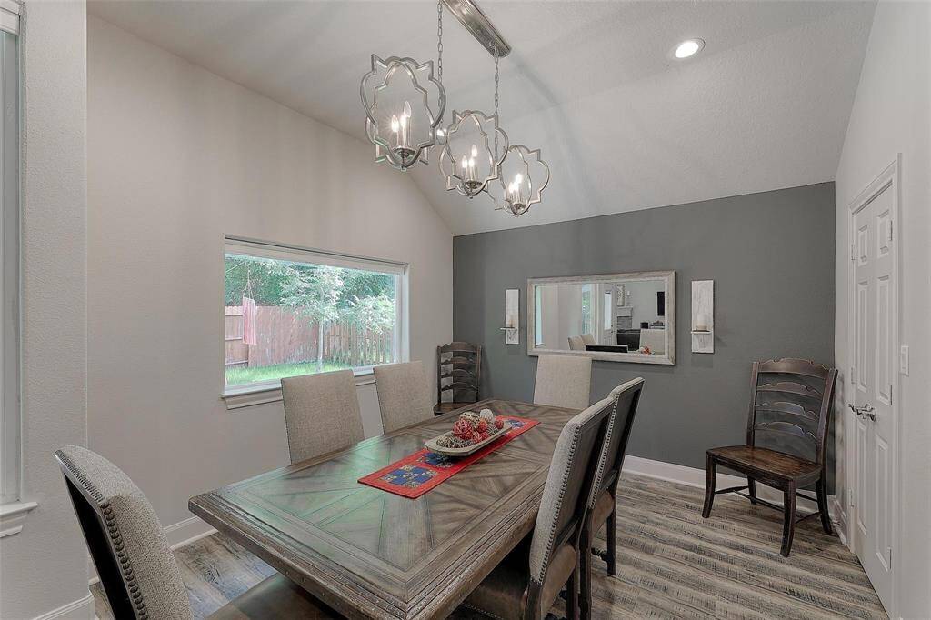 Bright dining room with updated lighting, high ceiling and large window for natural light.