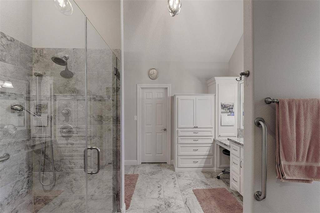 Gorgeous primary bath with seamless glass shower enclosure, built in storage and vanity area.