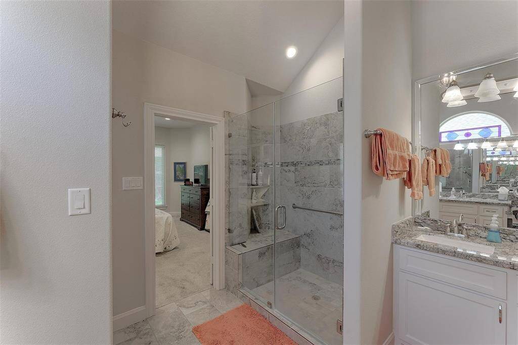 Another vanity area with view of the shower with a built in bench.