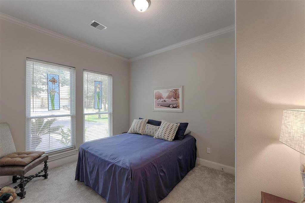 Bright guest bedroom with crown molding and double windows overlooking the front yard.