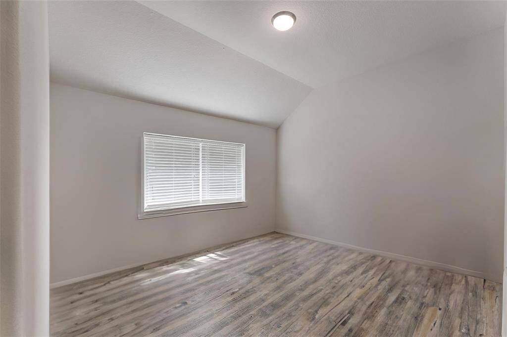 A second guest bedroom also features high ceilings, neutral paint and wood-look laminate floors.