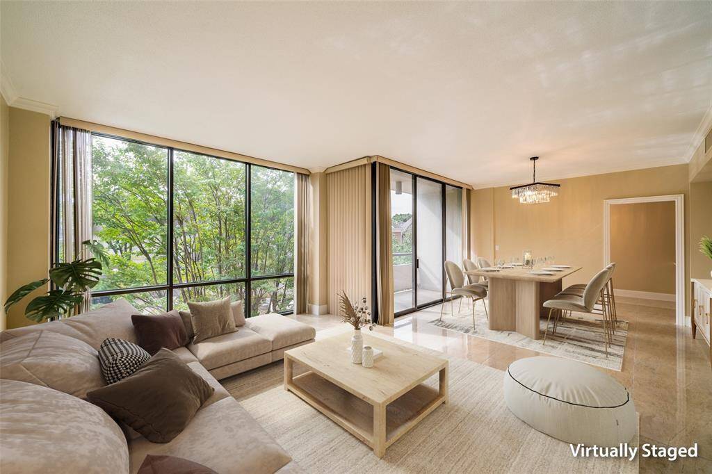 This virtually staged photo showcases a bright, open-concept living and dining area with large windows offering lush green views.