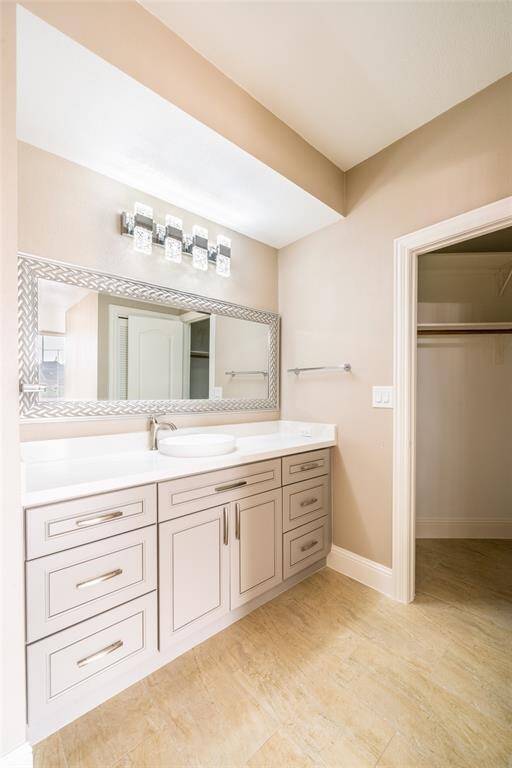 This bathroom features a sleek vanity with ample storage, a large framed mirror, modern lighting, and neutral tile flooring. It offers a clean and contemporary look, perfect for any home.
