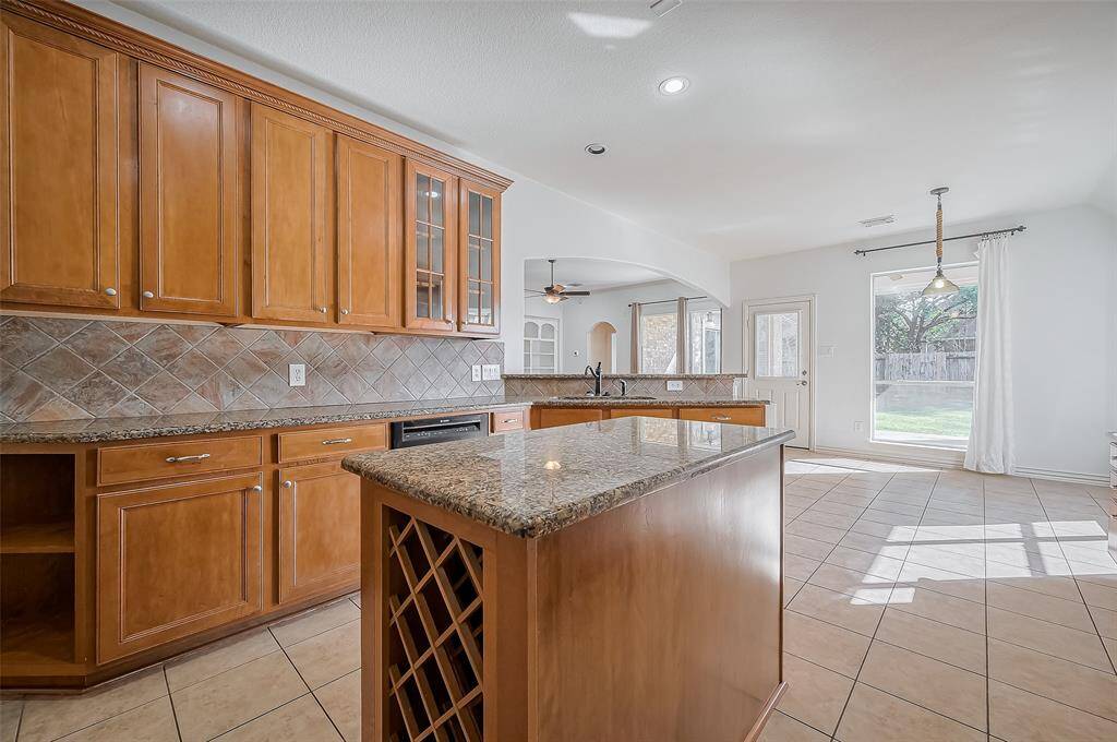 This bright kitchen is open to a sunlit breakfast area with large windows overlooking the backyard, offering a seamless flow for entertaining and family gatherings.