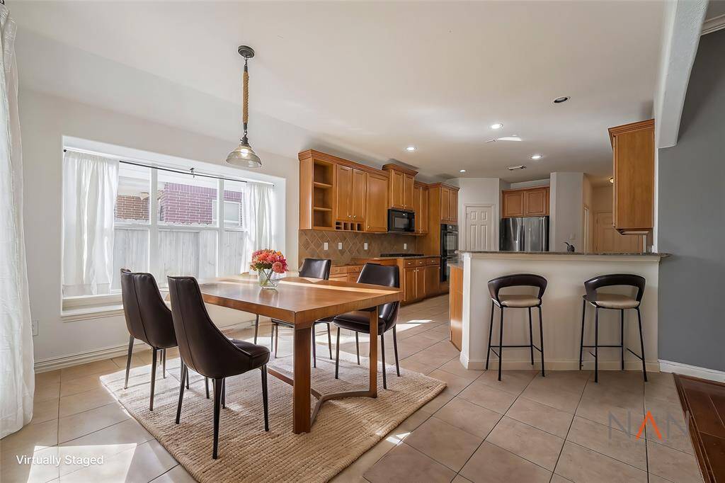 This bright, open kitchen flows into a sunny breakfast area with large windows. The breakfast bar offers extra seating, making it a perfect spot for meals and casual gatherings.