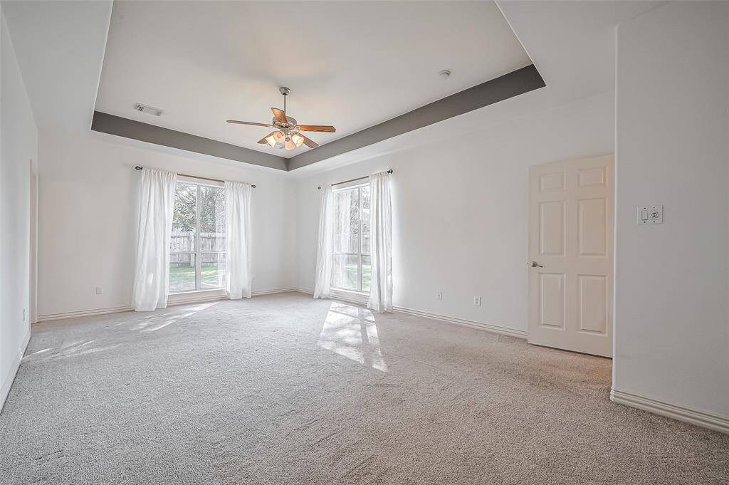 Another view of this amazing primary bedroom with a view to the backyard and large floor to ceiling windows.