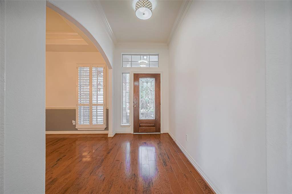 Welcome in to this beautiful home with engineered hardwood floors, a high ceiling, and an arched opening leading to the dining room with wood shutters.