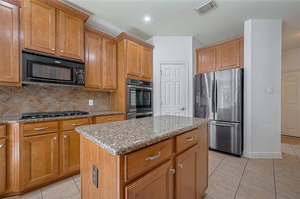 This kitchen features a double oven and a French door refrigerator. The central island offers additional prep space.