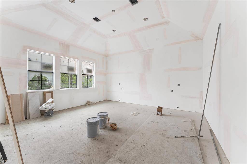 Spacious primary bedroom with 14' ceilings and plenty of natural light. A small entryway, before entering the bedroom, creates a defined space, a perfect place to showcase art.
