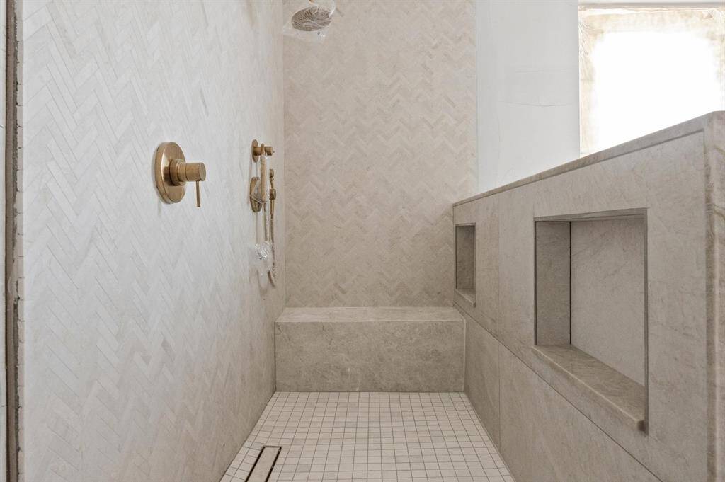Primary bathroom with marble shower wall and quartzite waterfall bench.