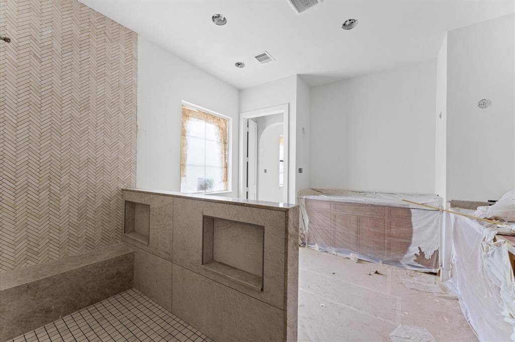 Custom white oak vanity cabinets are enhanced by Taj Mahal quartzite countertops.