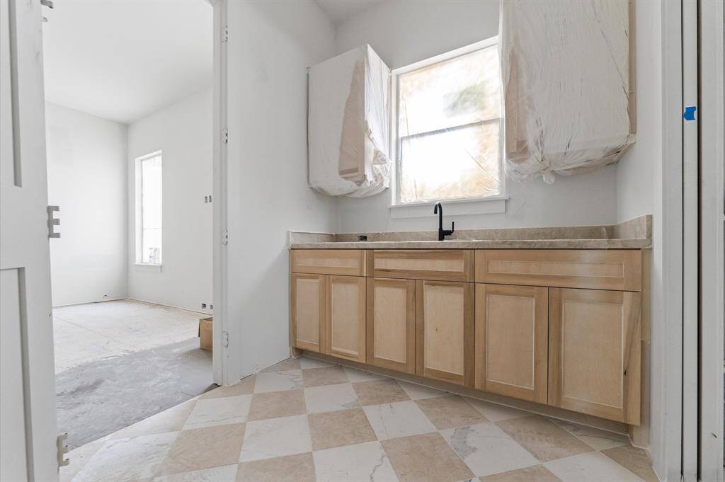 Finishes for the laundry room include Taj Mahl quartzite countertop and mosaic tile floors.