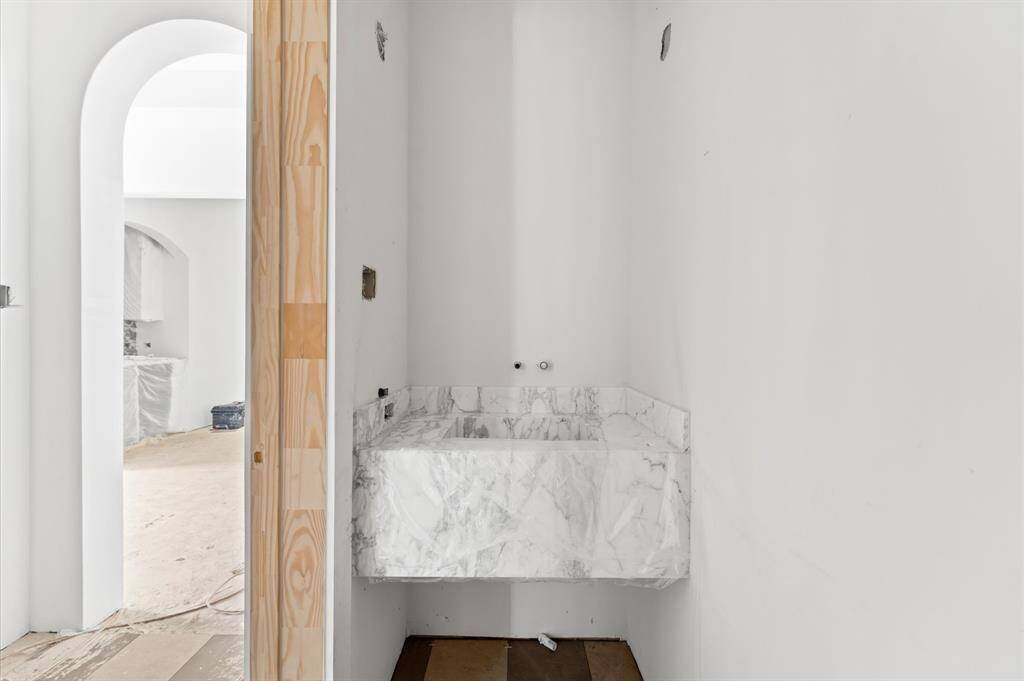 Powder bath has floating marble vanity with integrated sink.