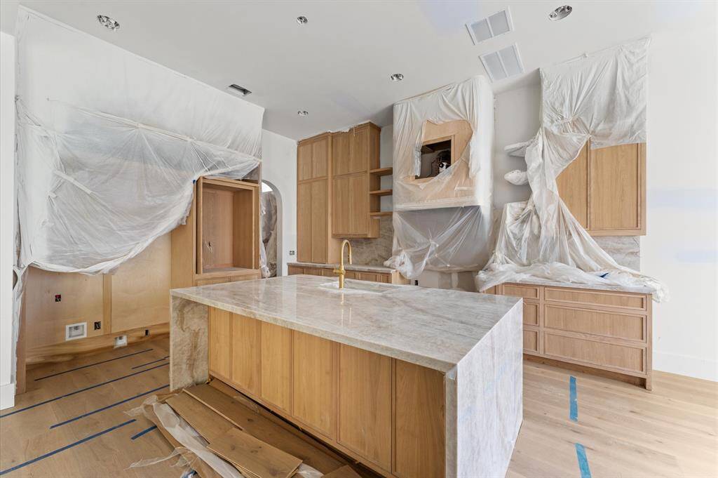 The gourmet kitchen boasts white oak custom cabinetry, Taj Mahal quartzite countertops, custom curved vent hood and built-in paneled refrigerator.