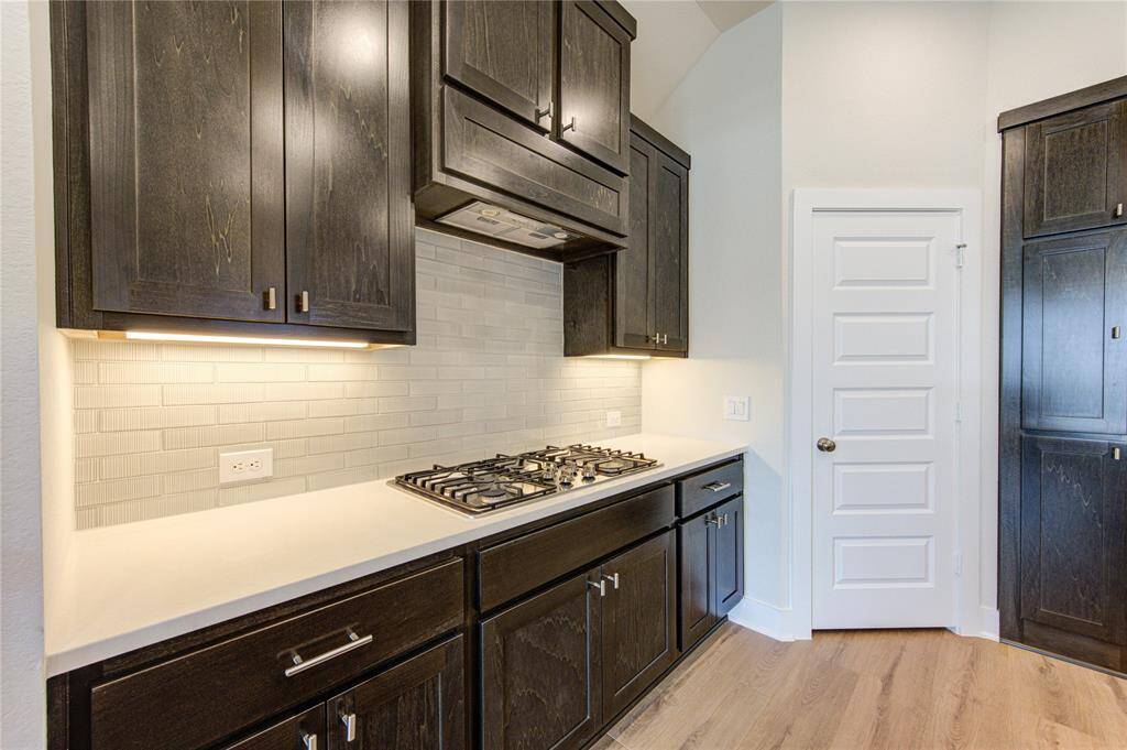 Gas cooktop, under cabinet lighting and designer backsplash.