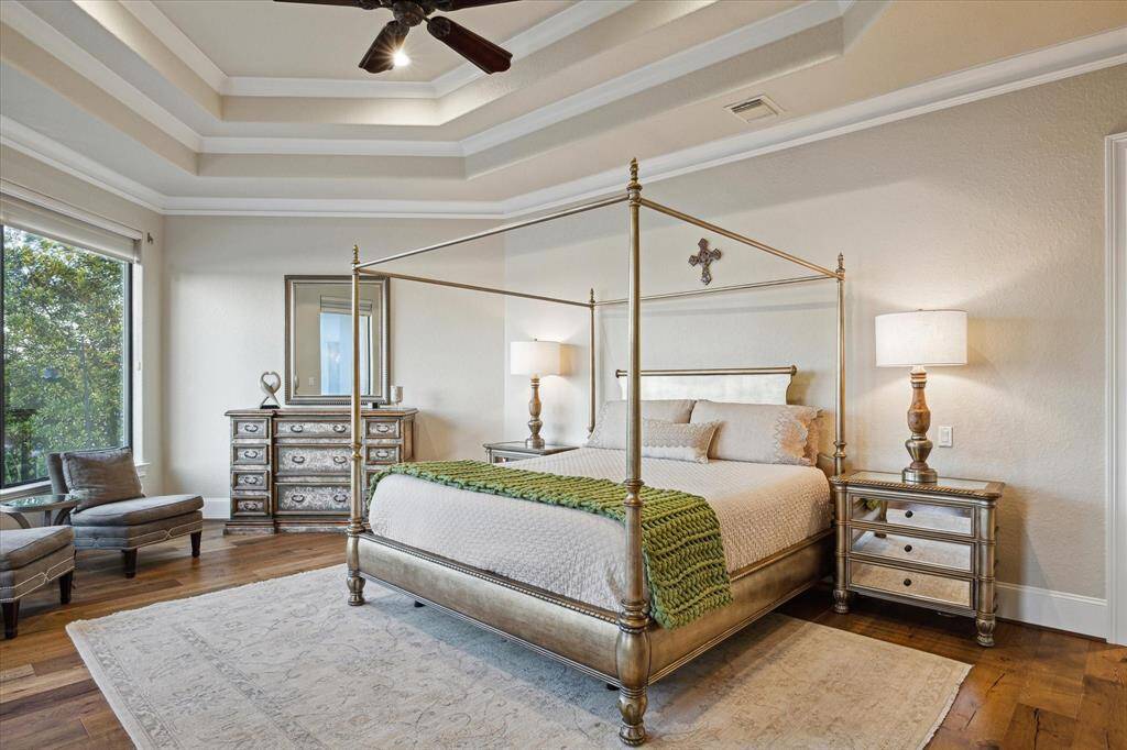 SPACIOUS PRIMARY SUITE WITH WOOD FLOORS AND A DOUBLE COFFERED CEILING WITH CROWN MOLDING.