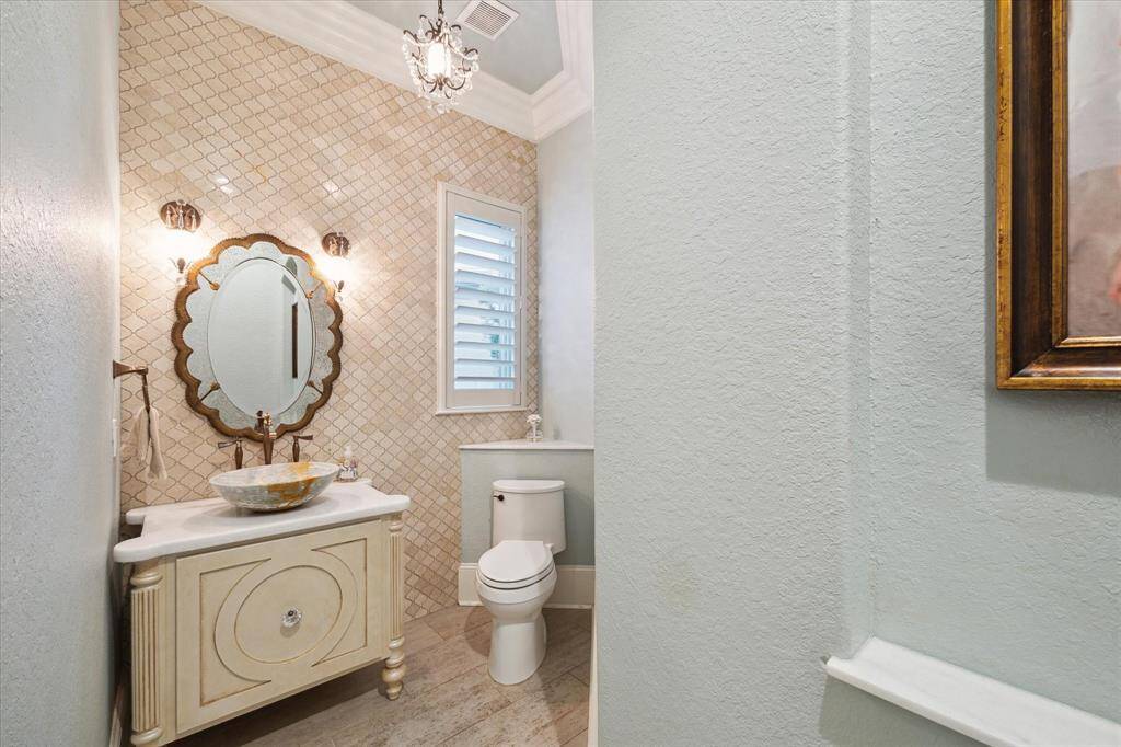 1ST LEVEL HALF BATH WITH EXTENSIVE CUSTOM TOUCHES INCLUDING AN ANTIQUE STYLE VANITY WITH SCONCE LIGHTING AND A TILED ACCENT WALL.