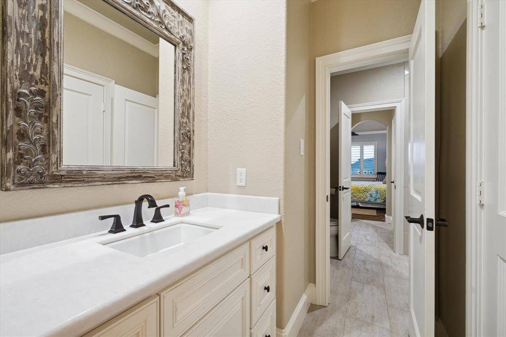 UPDATED HOLLYWOOD BATH WITH BEAUTIFUL FRAMED MIRRORS AND A WALK-IN SHOWER WITH CUSTOM TILE SURROUND AND FRAMELESS GLASS ENCLOSURE.