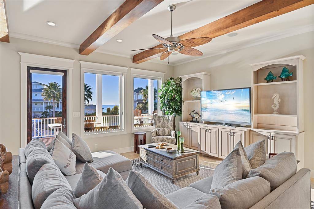 Another view of the living room showcasing picture windows and access to the deck