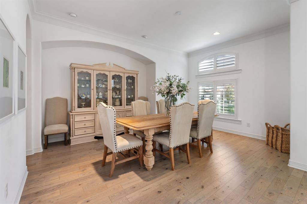 This bright dining room has hardwood floors. The natural light pours in through the arched windows with plantation shutters.